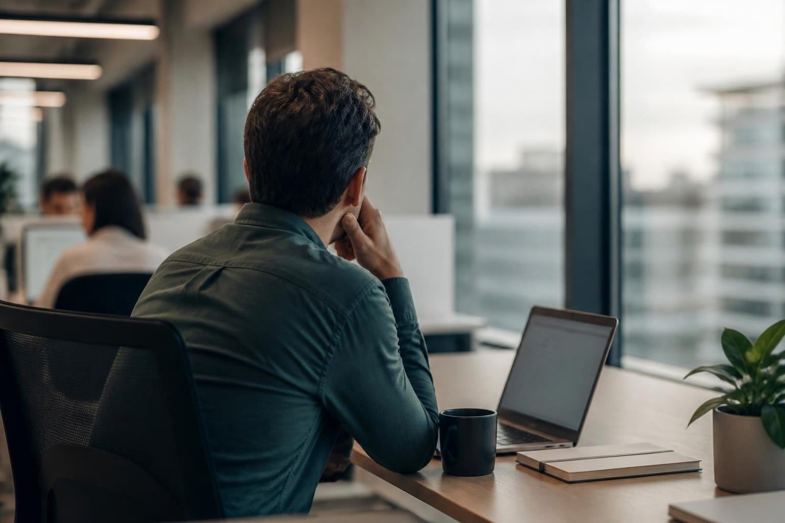Salarié pensif devant une fenêtre de bureau